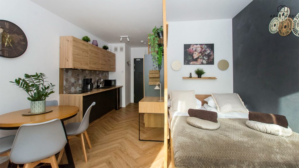 Cocina americana con cafetera y microondas, junto a la mesa y la cama