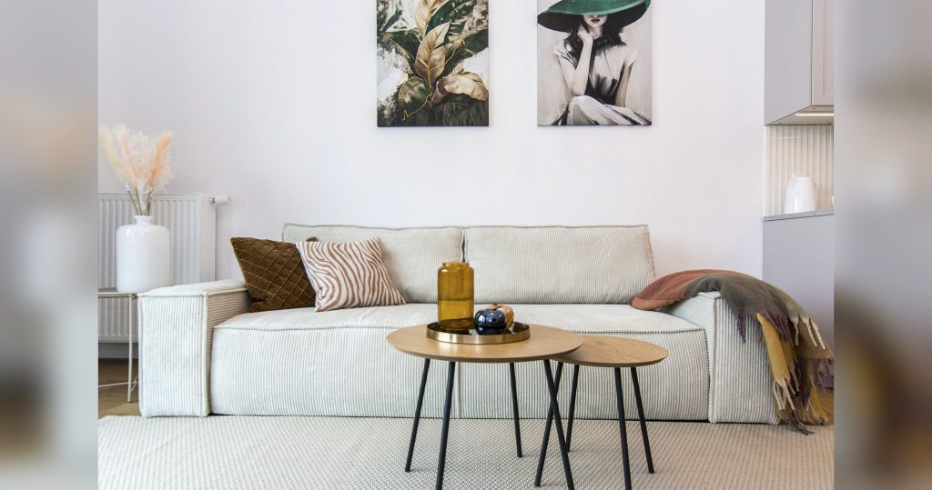 Salón en el apartamento: sofá claro, mesas de centro y gráficos en la pared