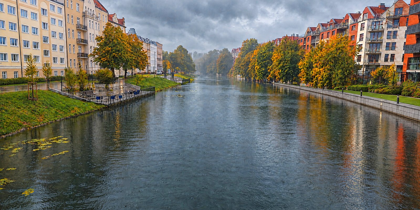 Canal de Nowa Motława en Gdańsk en un día lluvioso de otoño, muelle mojado junto a Kamienna Grobla y árboles en colores otoñales